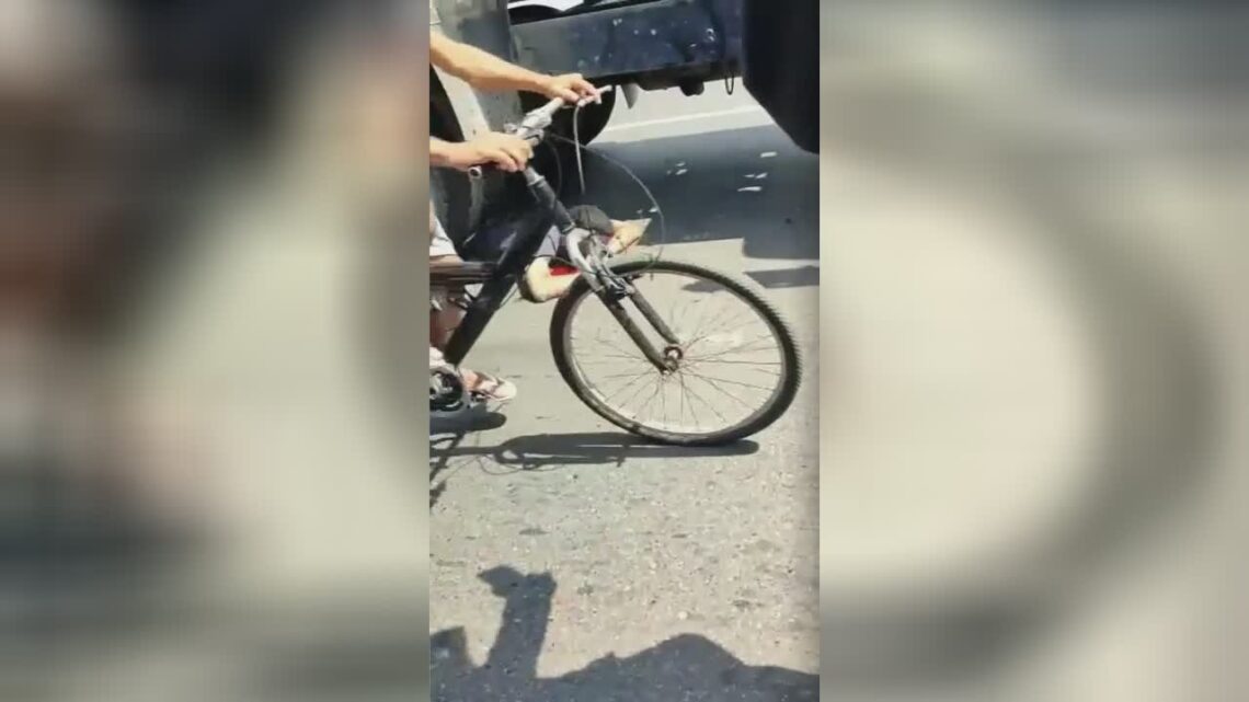 Gawkers recommend a man resting under the tires of a vehicle
