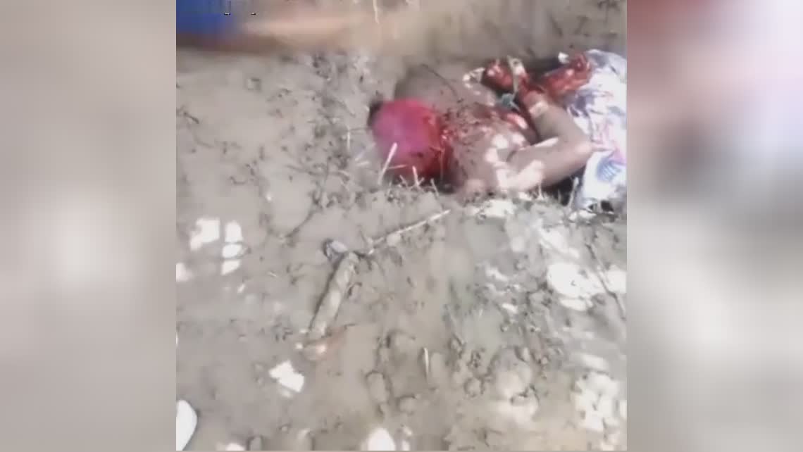 bound man in shallow grave gets pickaxe to the head